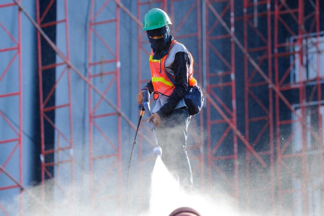 Cleaning worker spraying water on site